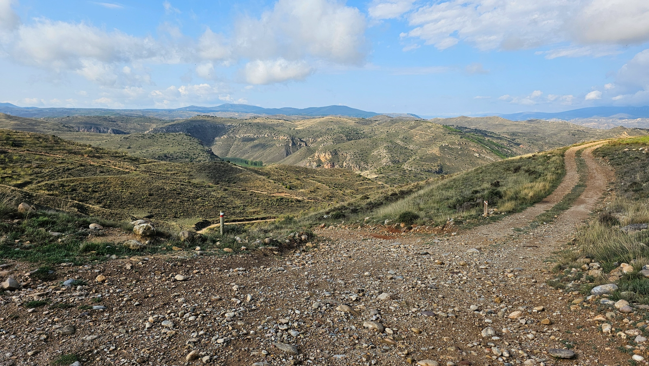 Piste caillouteuse serpentant entre des collines arides