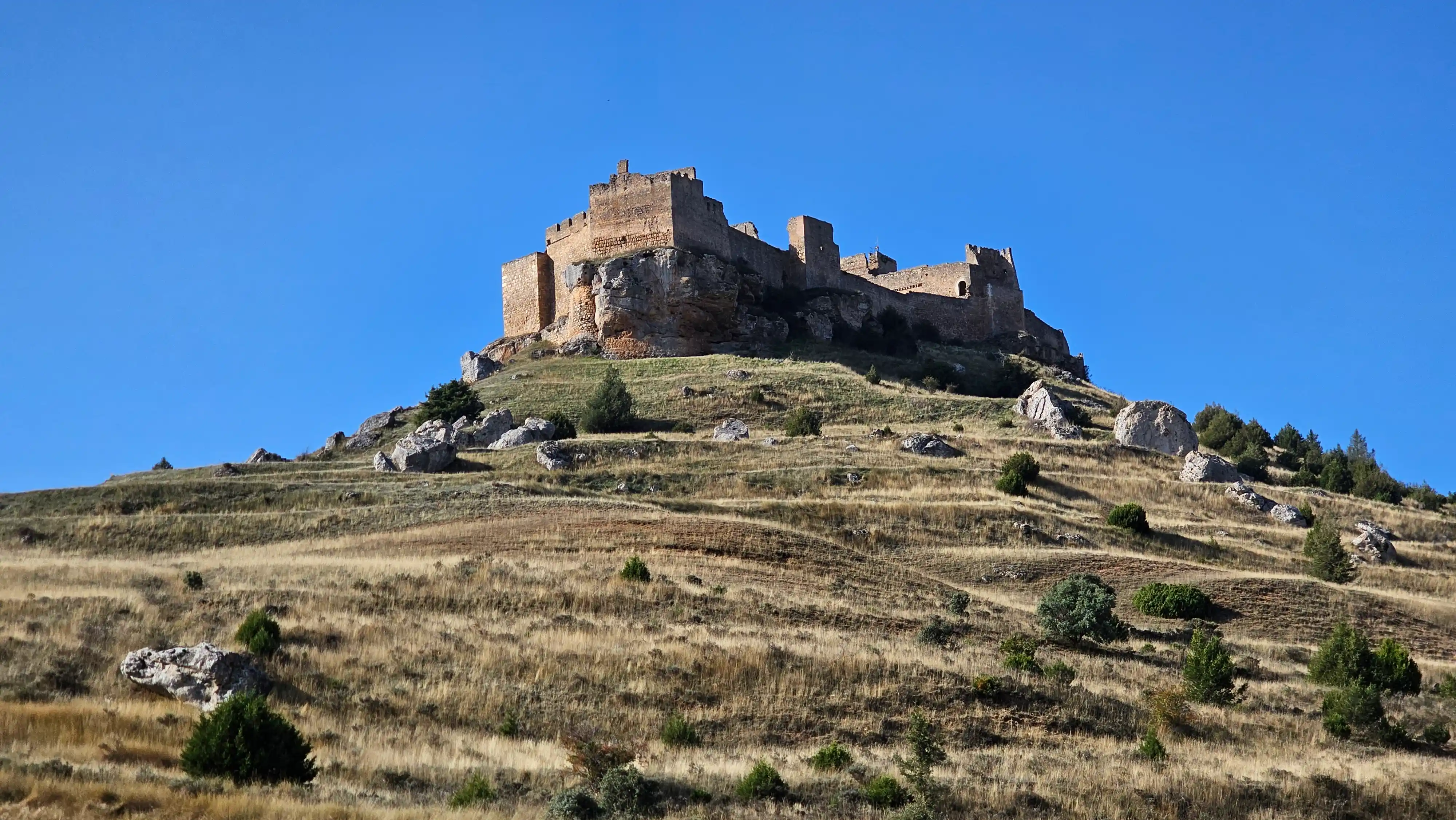 Château fort en ruine perché sur une colline sèche sous un ciel bleu