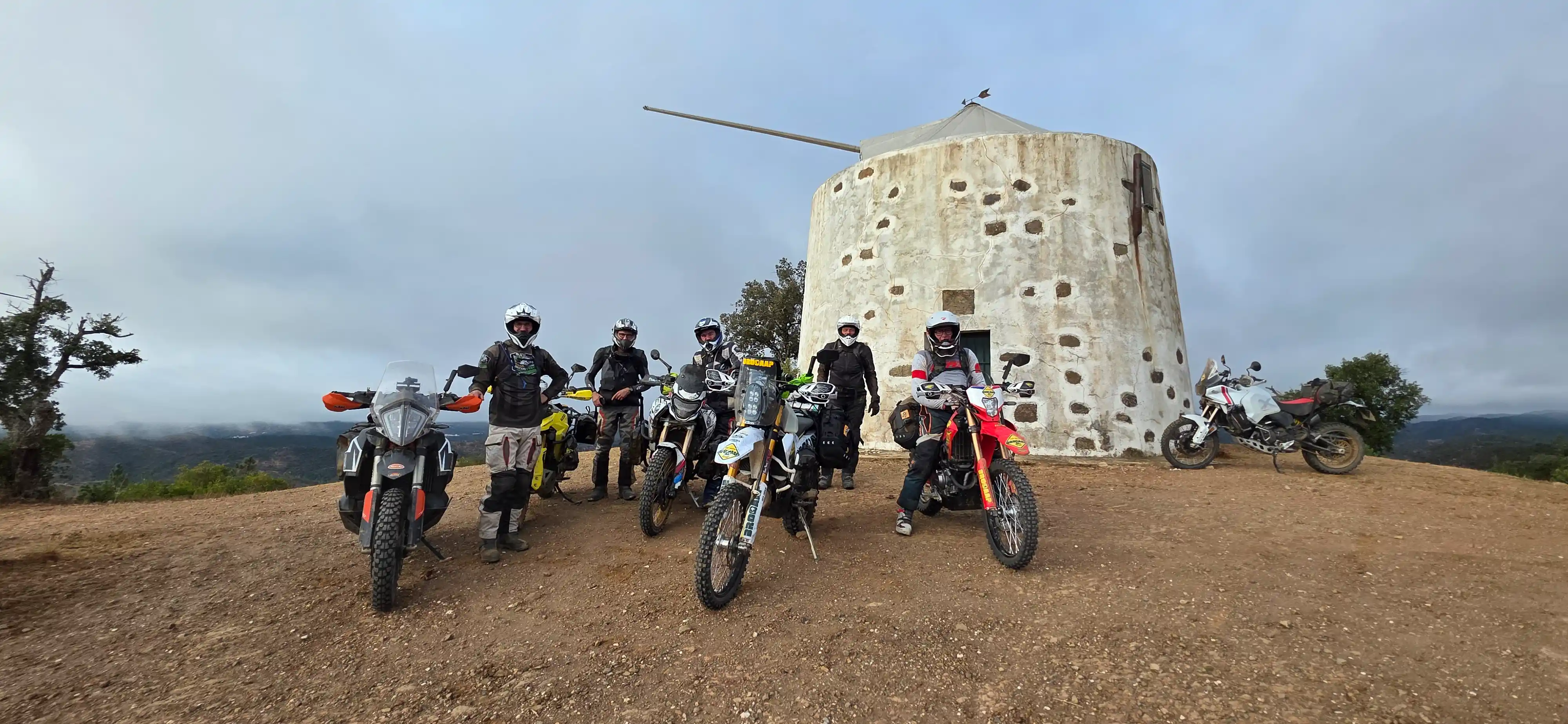 Groupe de motards trail devant un ancien moulin blanc