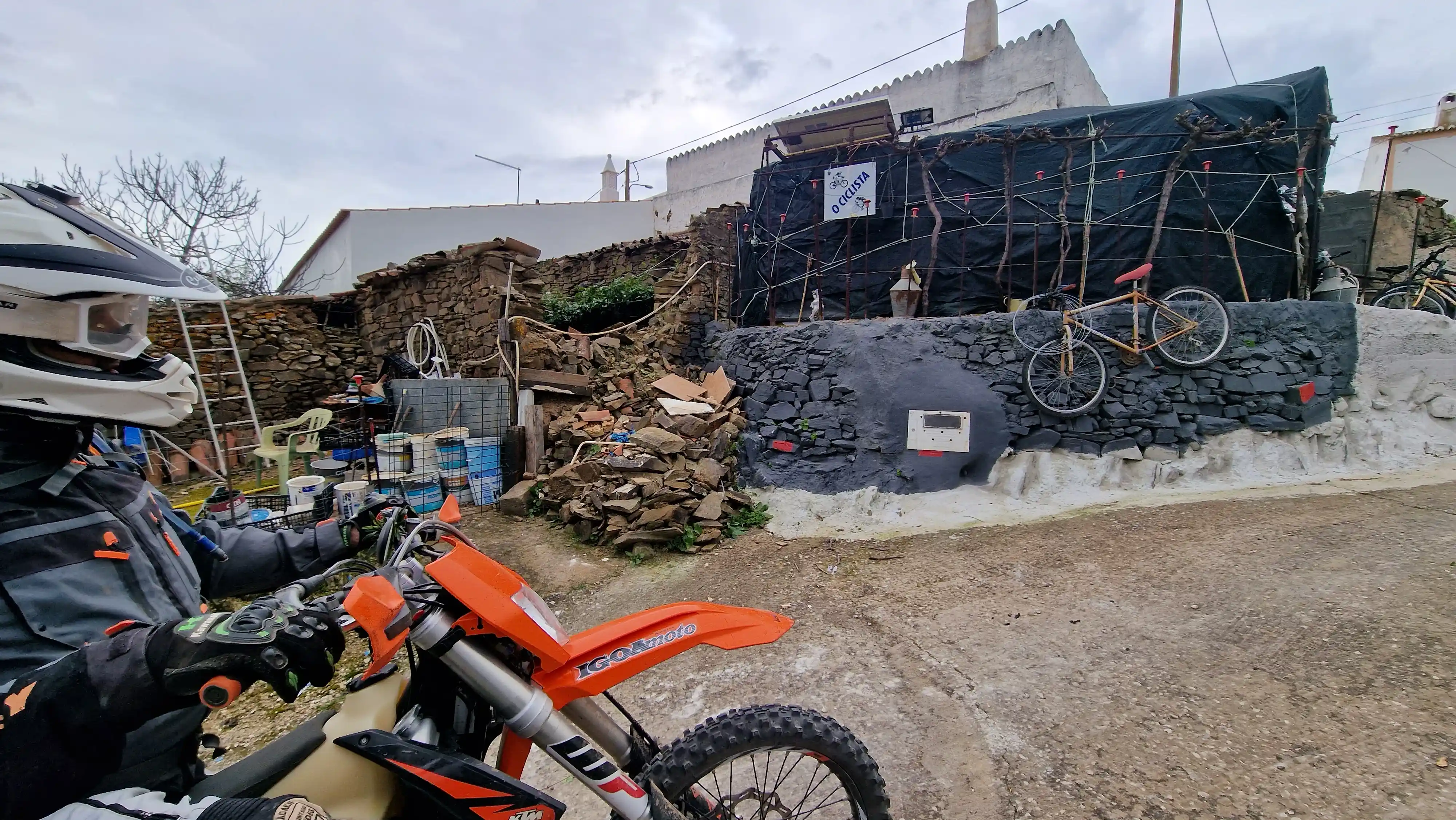 Moto d’enduro garée devant une maison décorée d’objets de récupération
