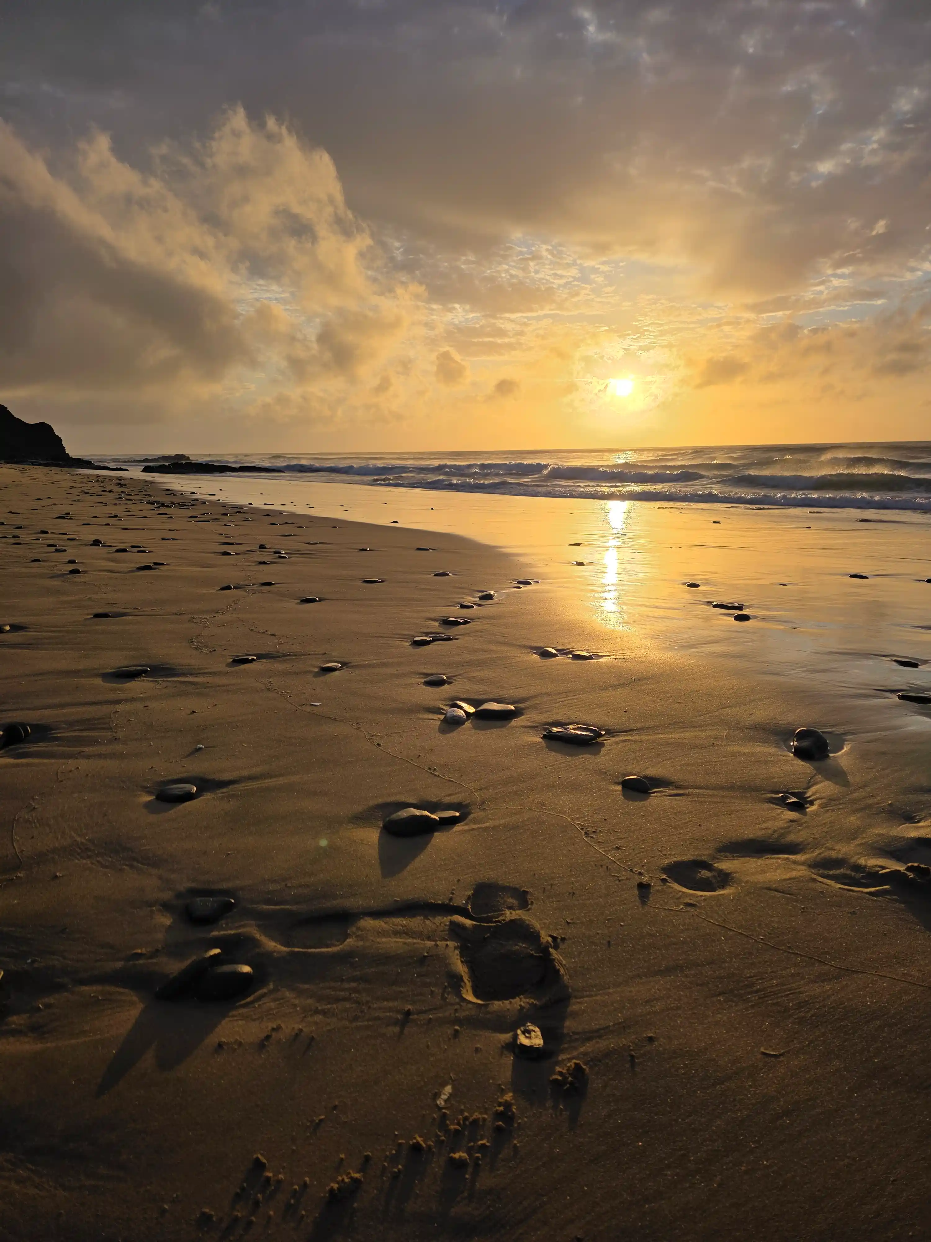Plage au coucher du soleil avec empreintes de pas dans le sable