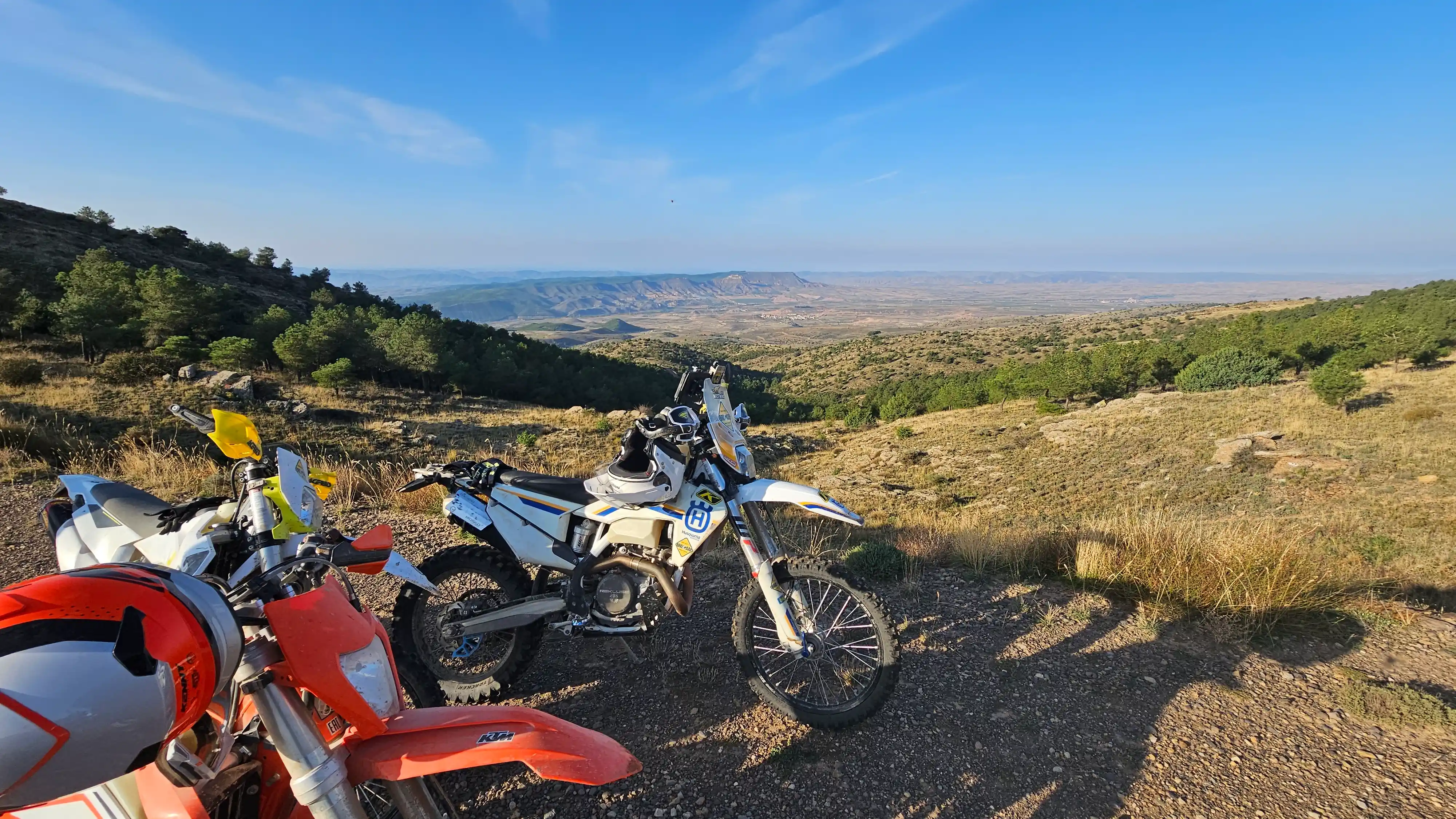 Motos d’enduro garées sur une piste dominant une plaine