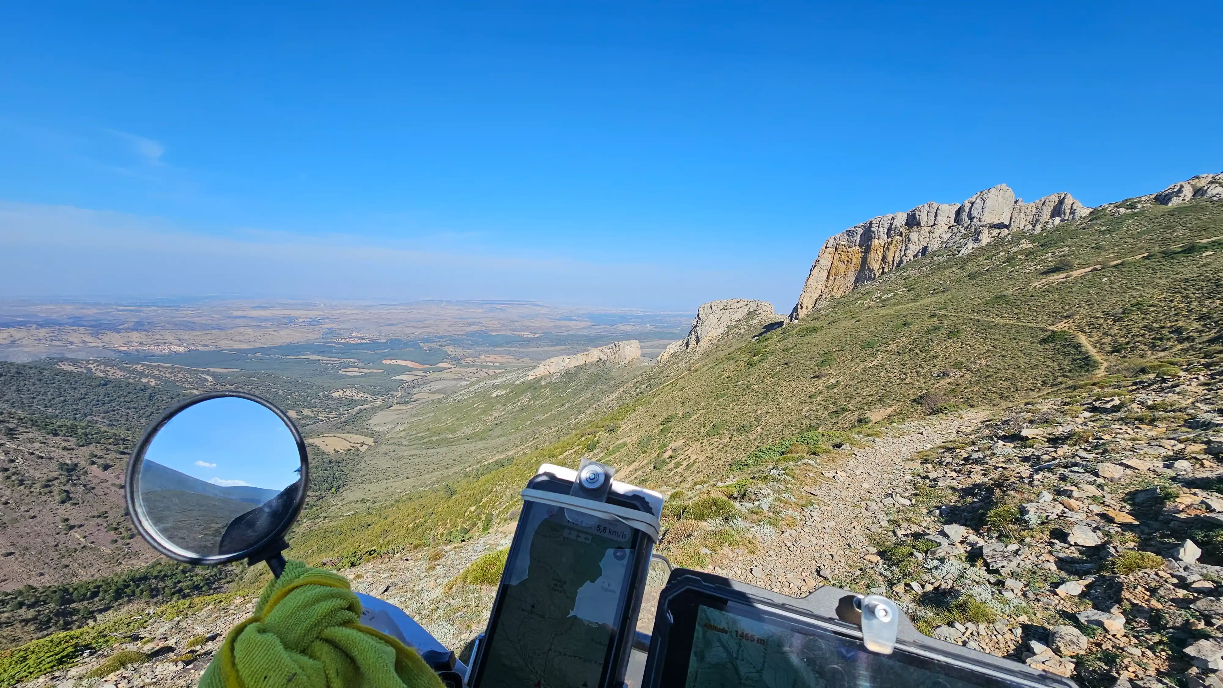 Piste de crête et plaine aride vues depuis le guidon d’une moto