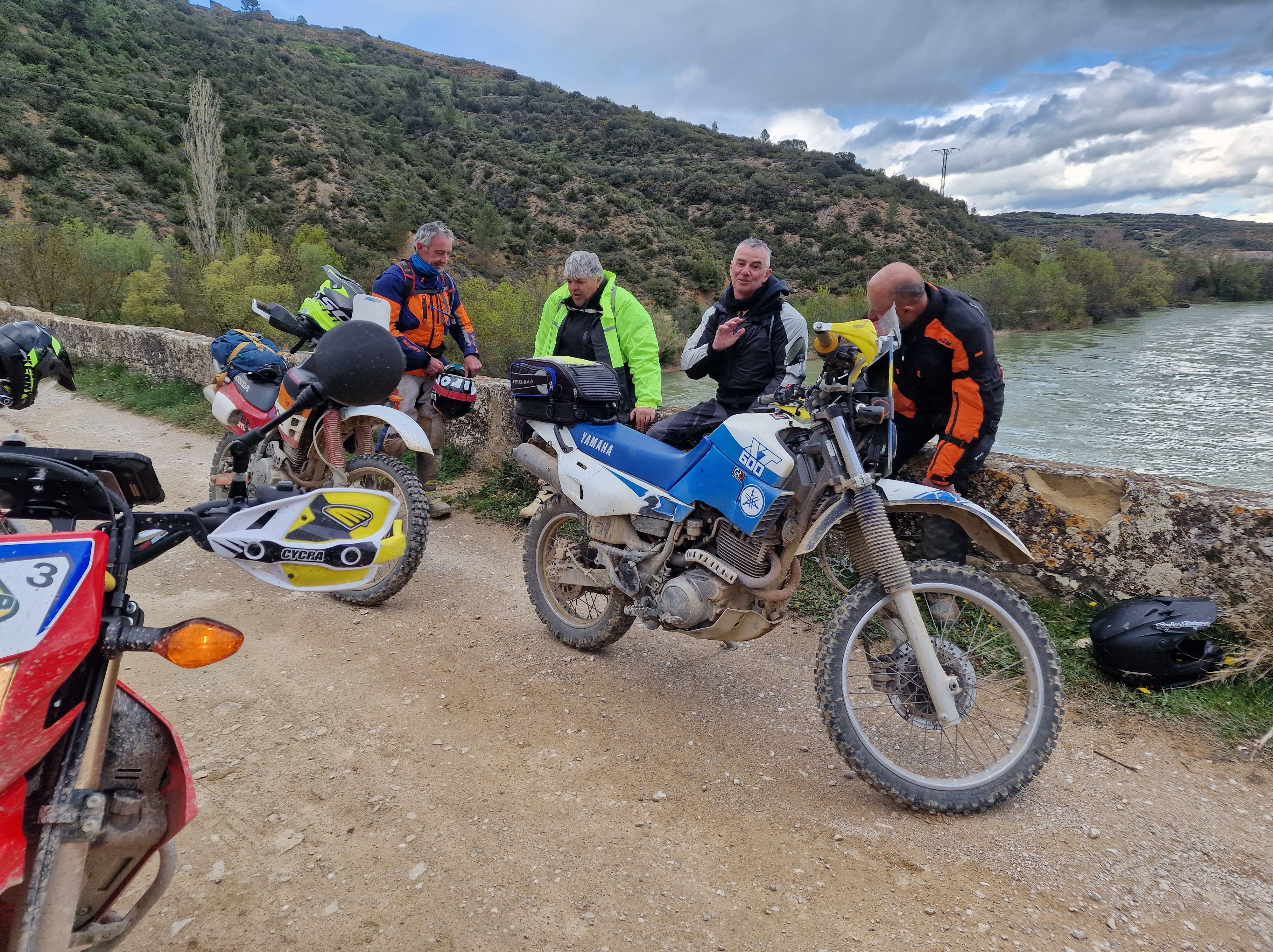 Motards en pause au bord d’une rivière avec leurs motos d’enduro