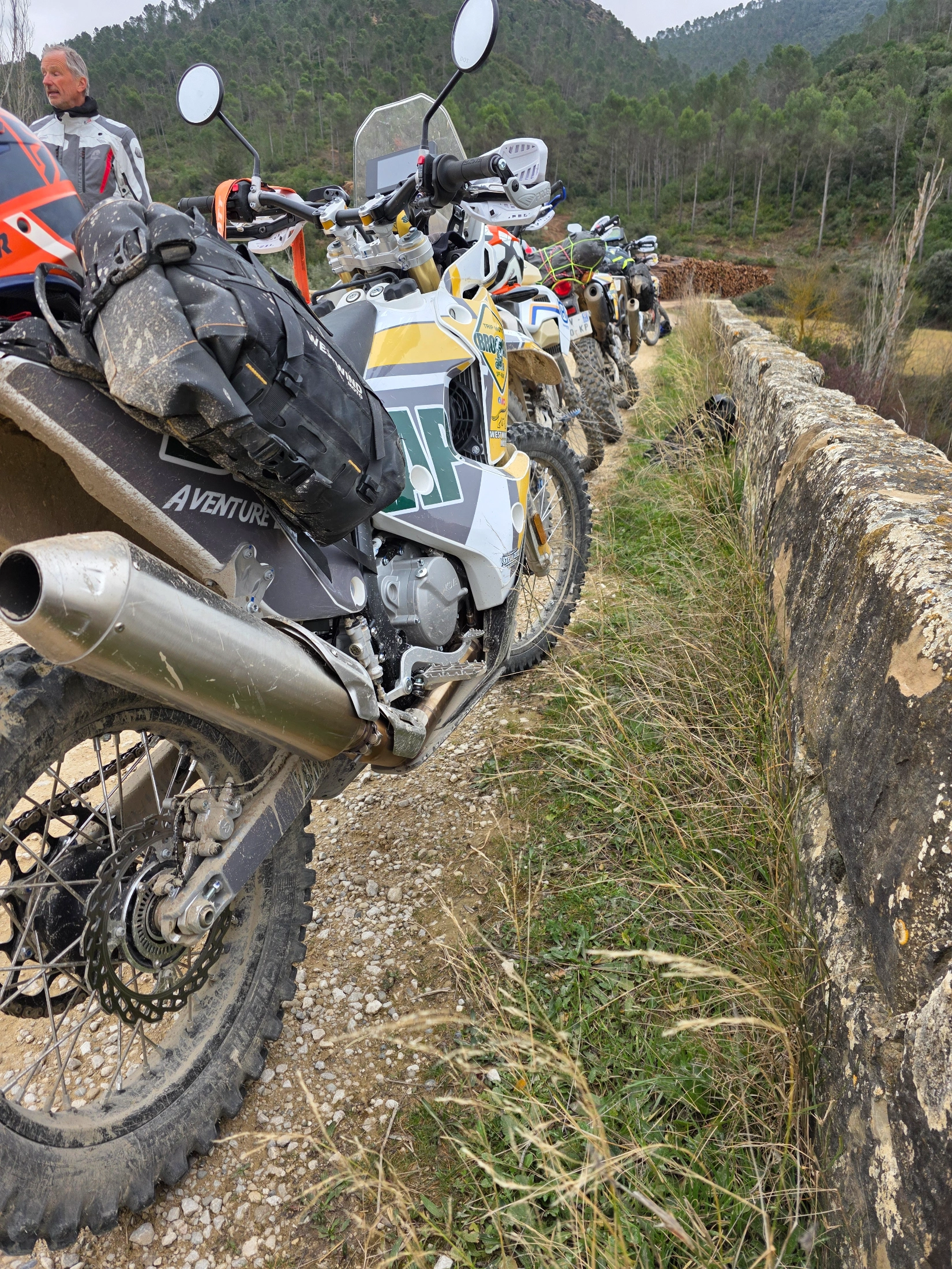 Motos trail garées le long d’un muret de pierre en montagne