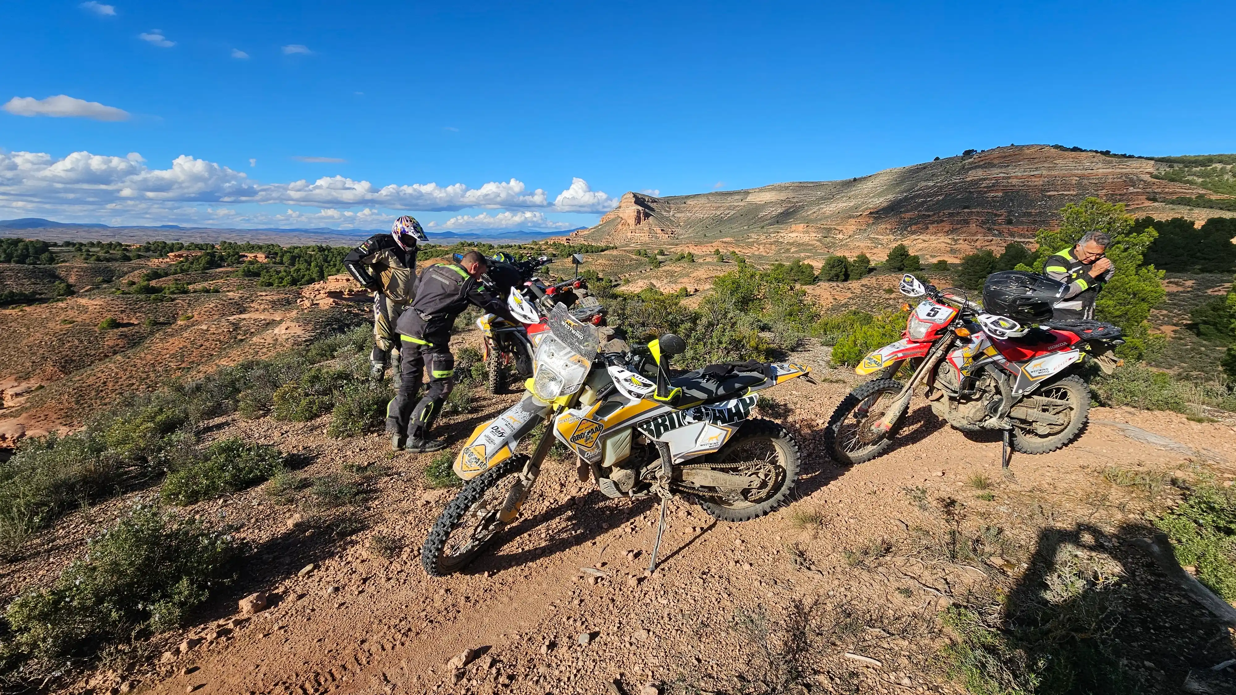 Deux motards et leurs motos trail sur une piste de terre rouge