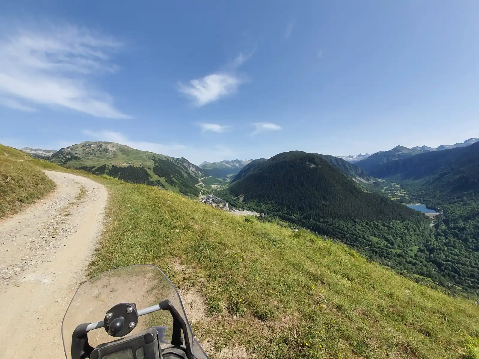 Piste de crête dominant une vallée des Pyrénées, vue depuis la moto