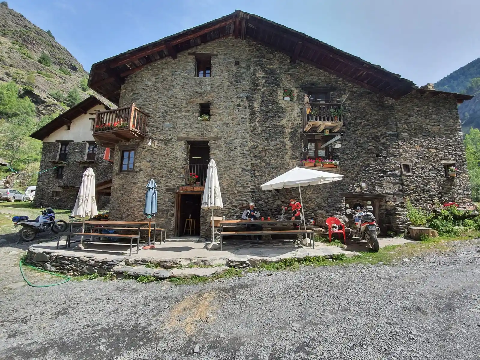 Auberge en pierre et motos garées dans un hameau des Pyrénées