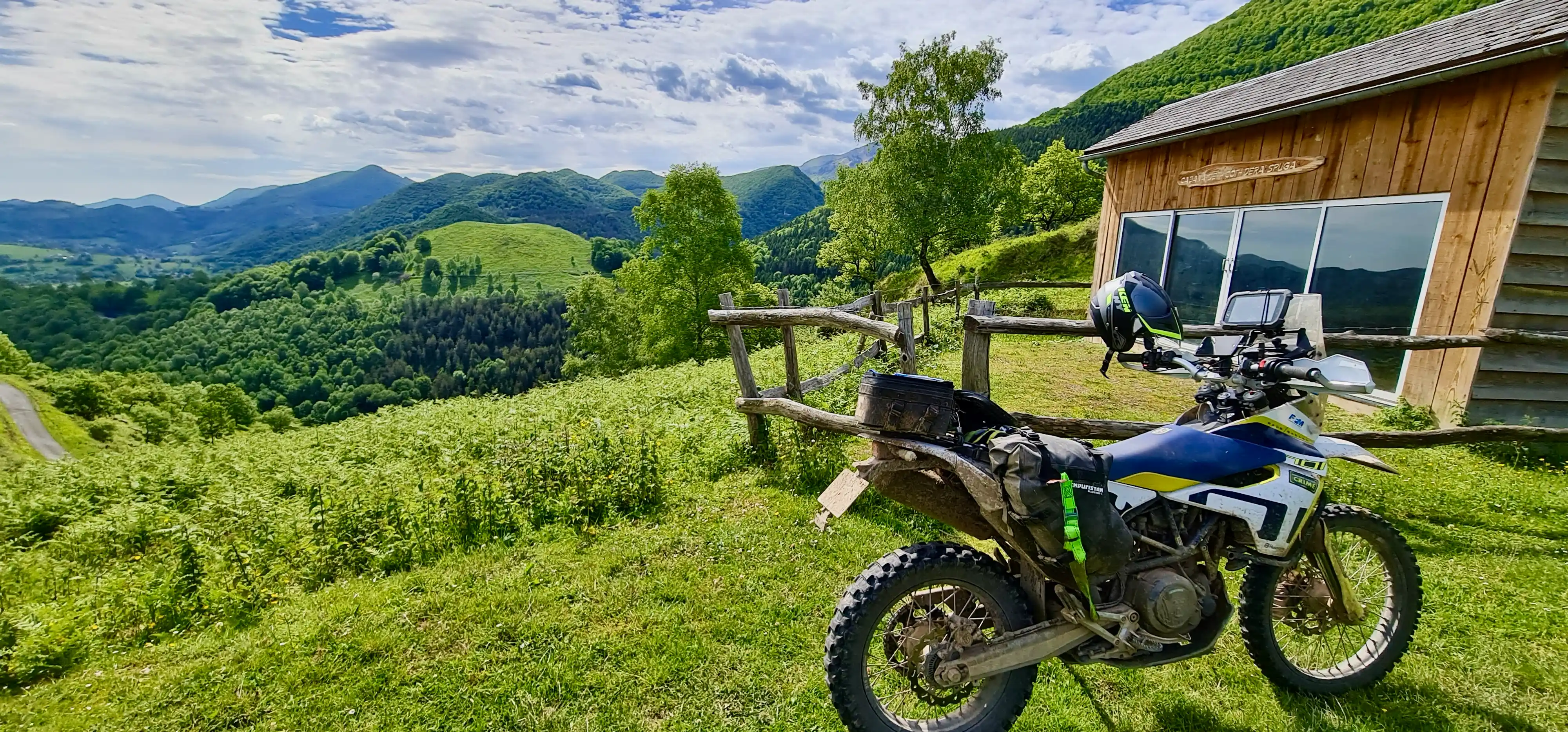 Moto d’enduro garée près d’un refuge en bois face aux Pyrénées
