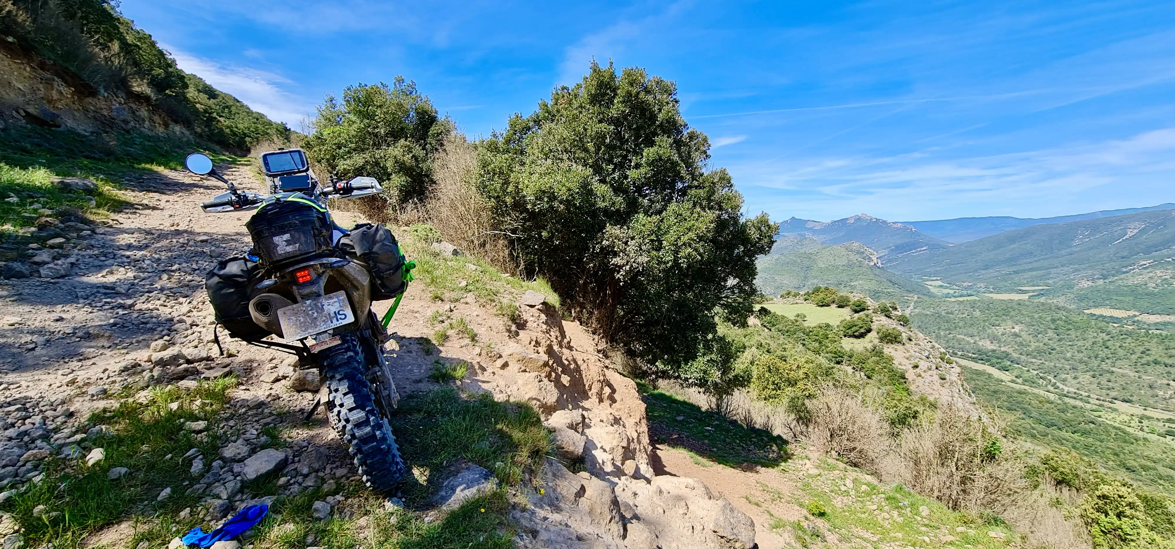 Moto trail garée sur un sentier rocheux dominant une vallée