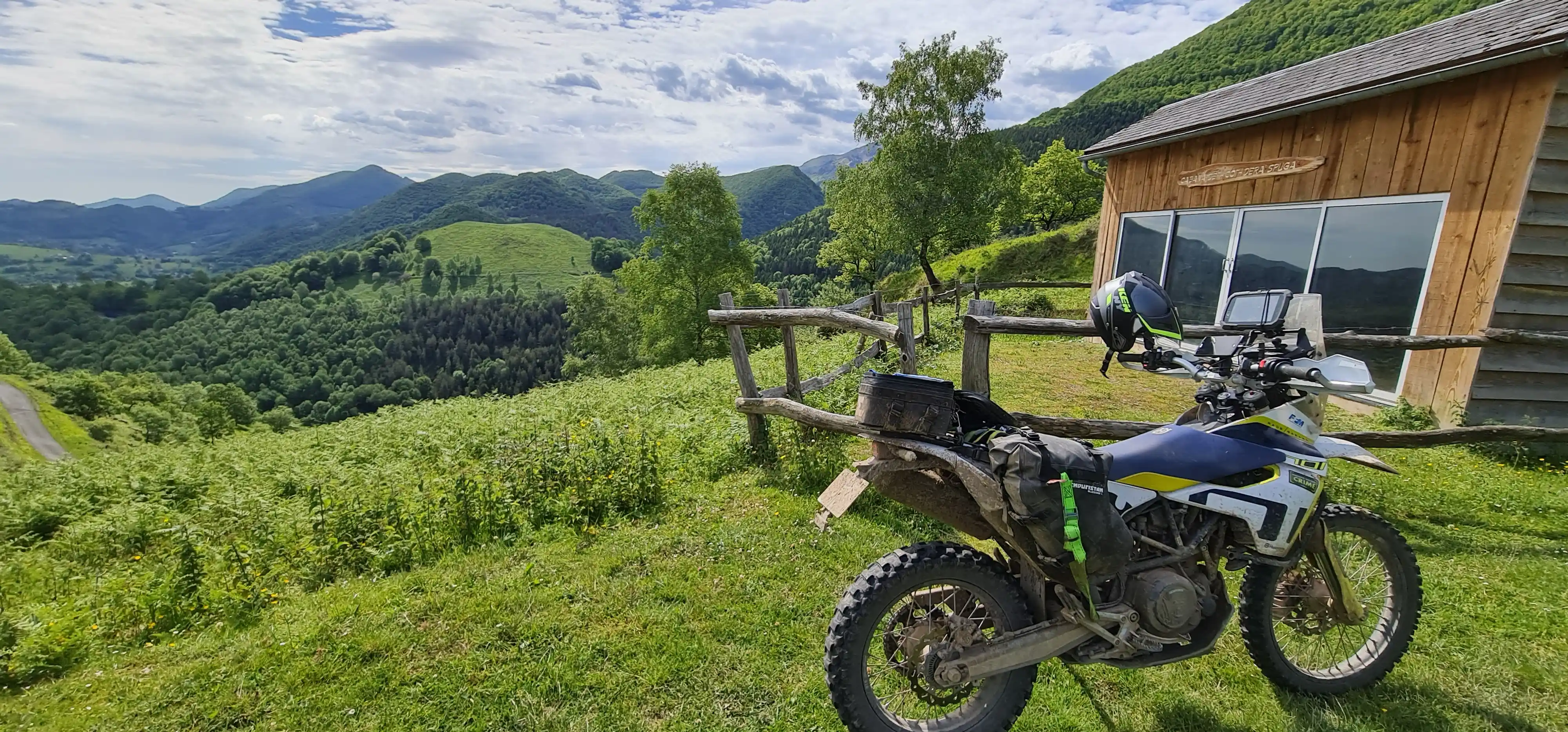 Moto d’enduro garée près d’un refuge en bois face aux Pyrénées