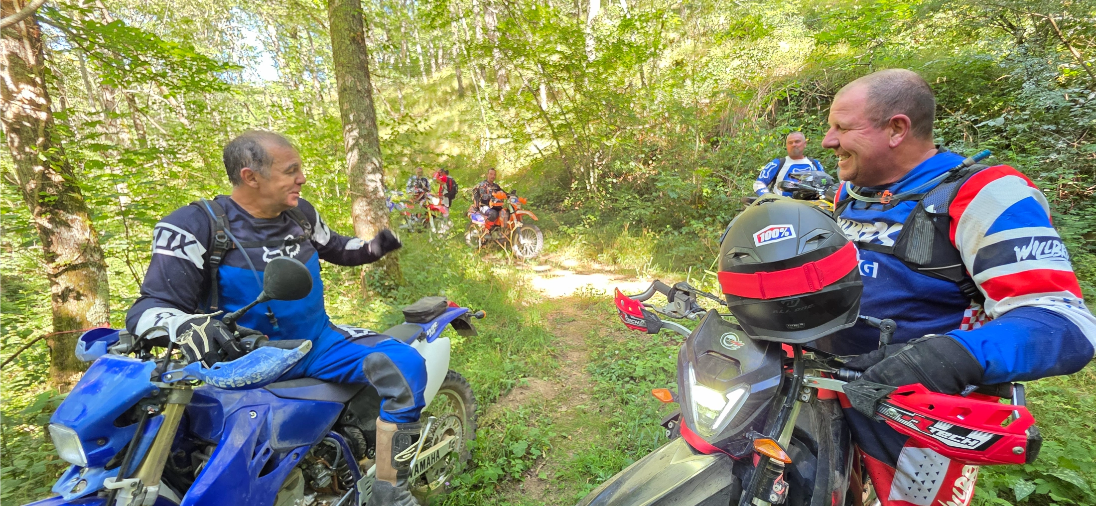 Deux motards souriants en pause dans un sous-bois