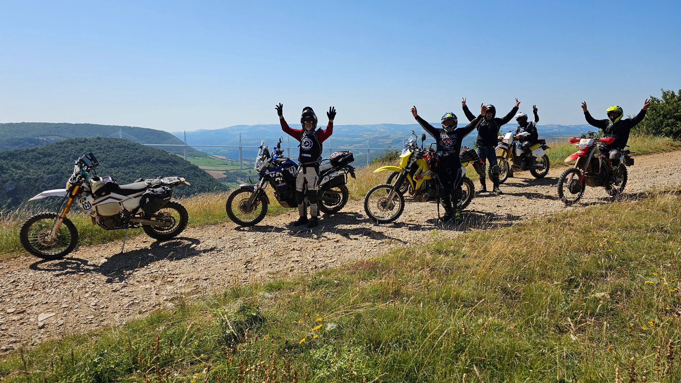 Motards bras levés près de leurs motos sur une crête de l’Aveyron