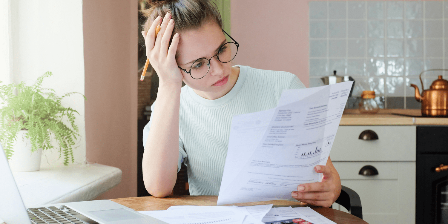 A concerned person looking at their bills to manage their debt from over-spending and not saving money.