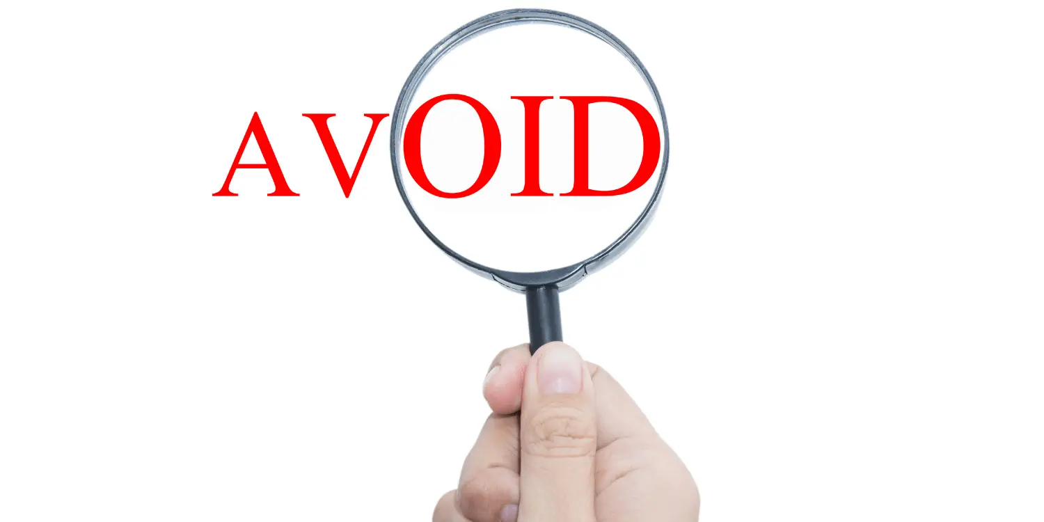 A hand holding a magnifying glass over the word avoid to stay away from predatory lending.