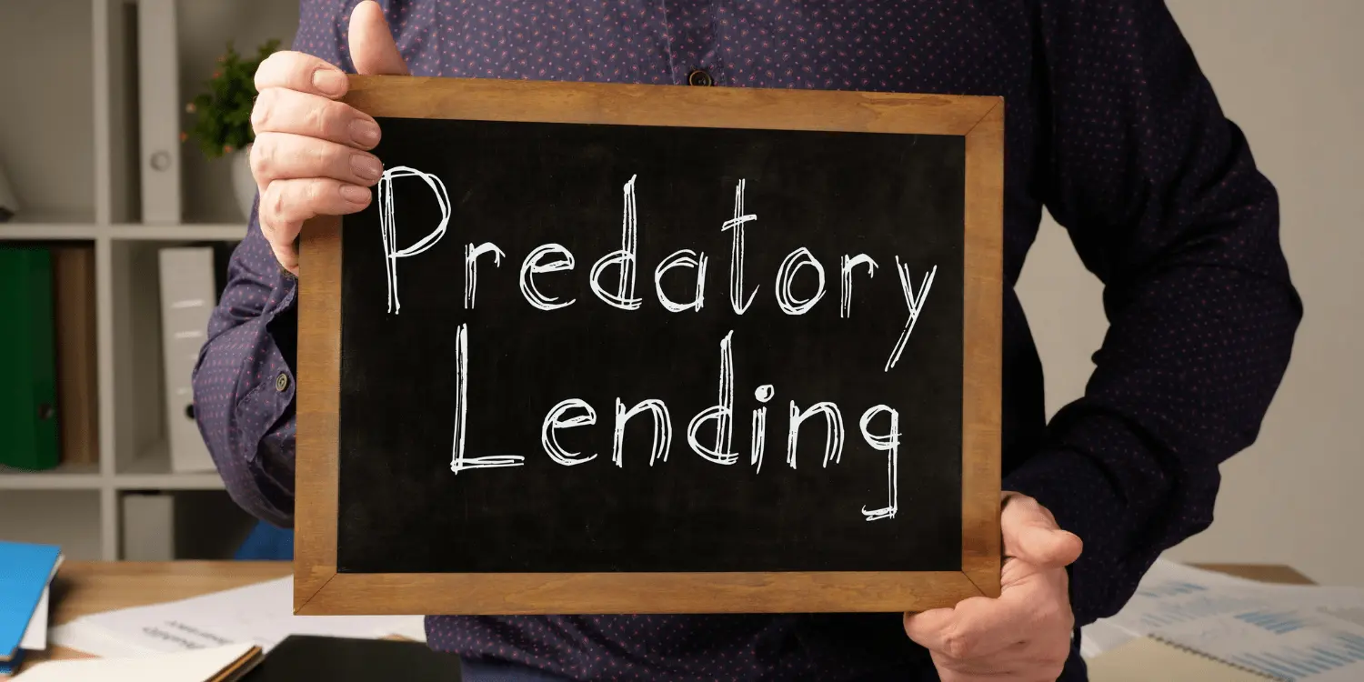 A person holding a chalkboard with the words "predatory lending" written on it.