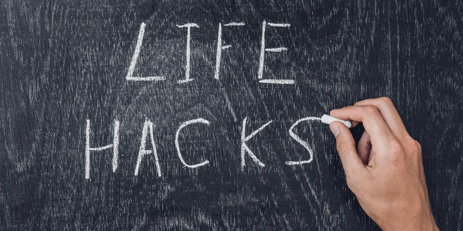 A hand writing the words life hacks on a blackboard that people wish they knew.