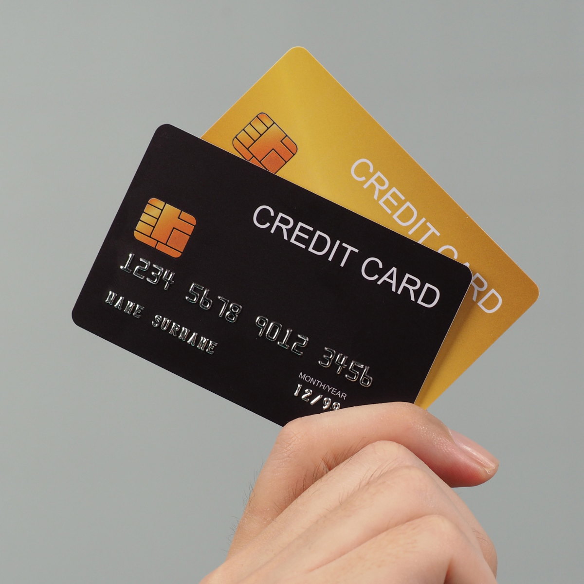 A hand holding two different credit cards.