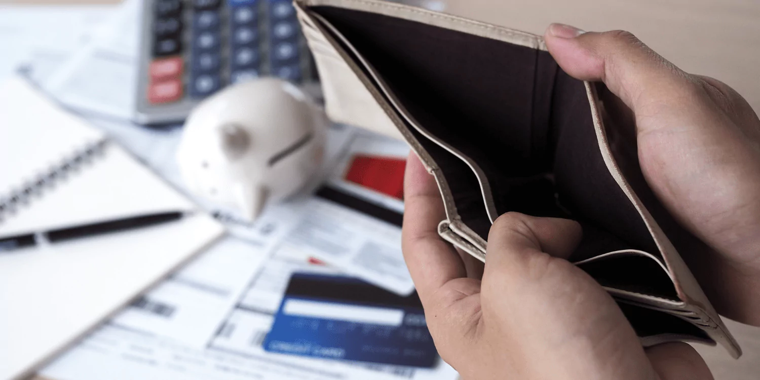 A hand grips an empty wallet next to a calculator and pen, illustrating considerations for choosing bankruptcy solutions.  