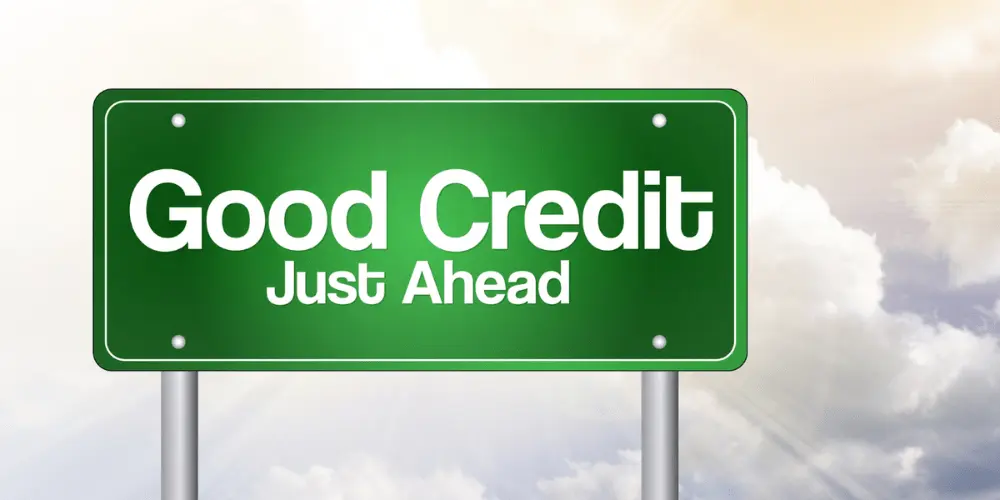 A vibrant green road sign reads 'Good Credit Just Ahead' against a sunlit cloud background, symbolizing the journey to improving credit scores. The sign represents the positive outcomes of managing credit well, such as higher credit limits, better credit mix, and maintaining a long and positive credit history, ultimately leading to excellent credit scores.