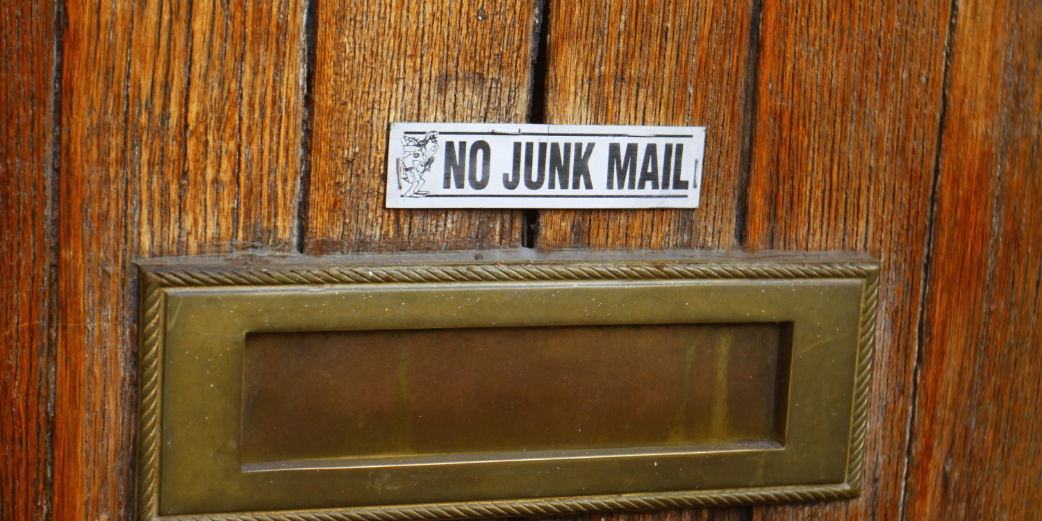 a door that has a mailing slit with a sign above it that states " No Junk Mail" to illustrate the desire to stop getting junk mail.