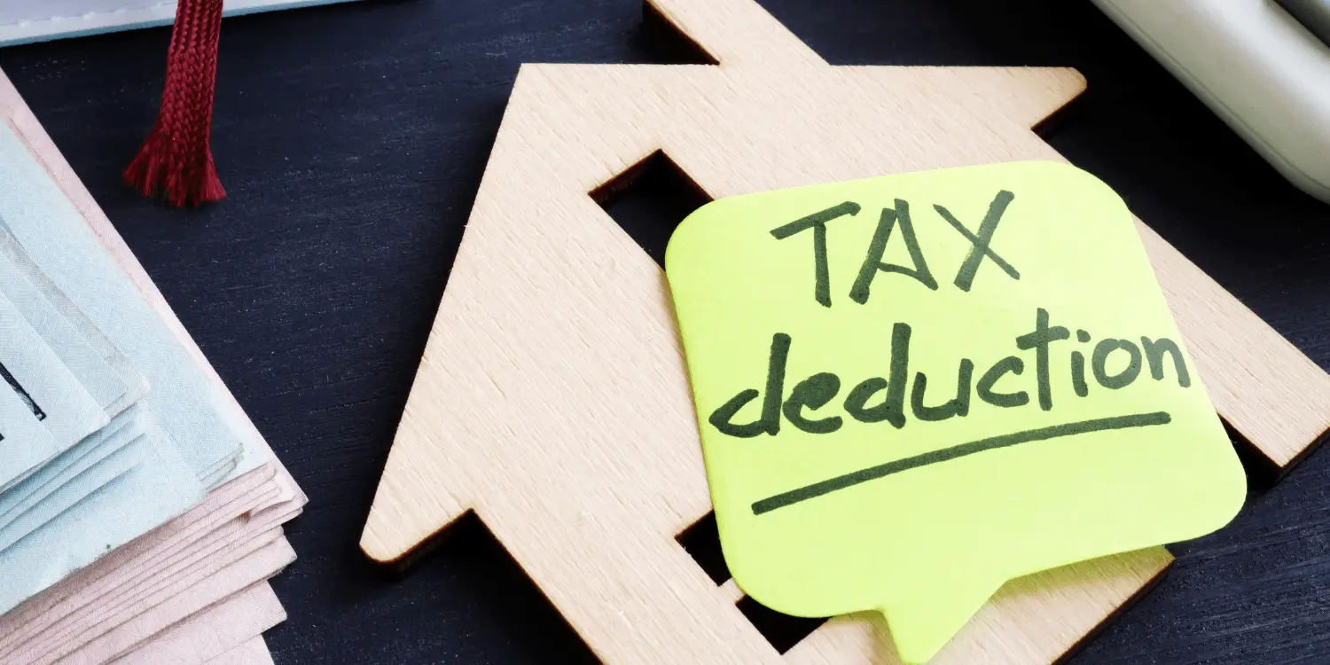 A cut out house from wood that has a sticky note that has tax deduction written on.