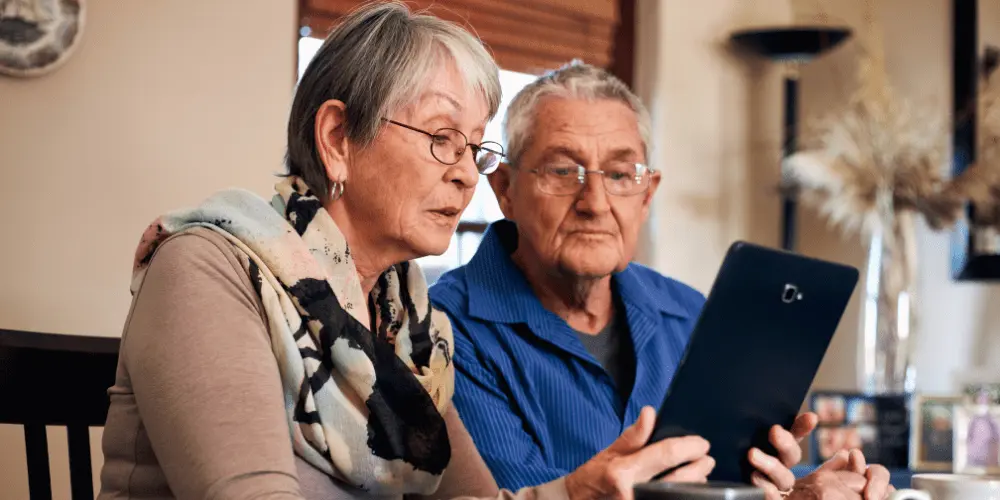 An older couple engaged with a tablet, considering the long-term financial benefits associated with reverse mortgages. 