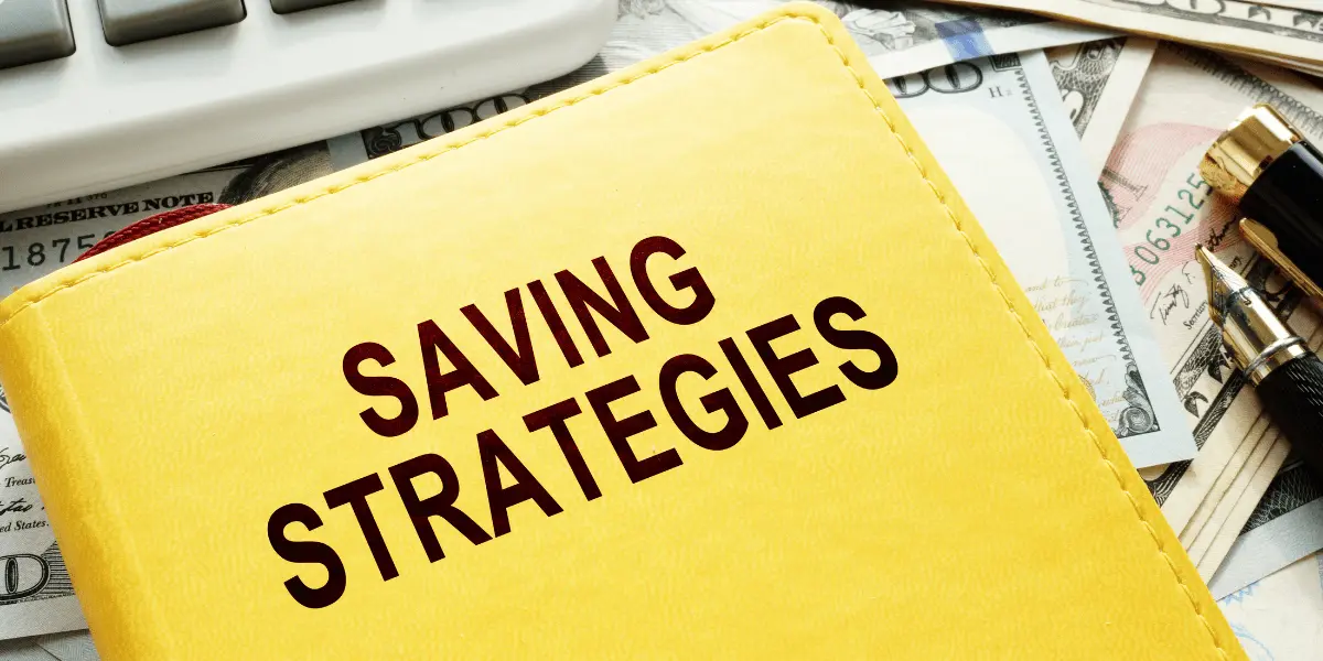 A yellow notebook labeled "Saving Strategies" resting on a background of dollar bills and a calculator, symbolizing applying chosen saving strategies.
