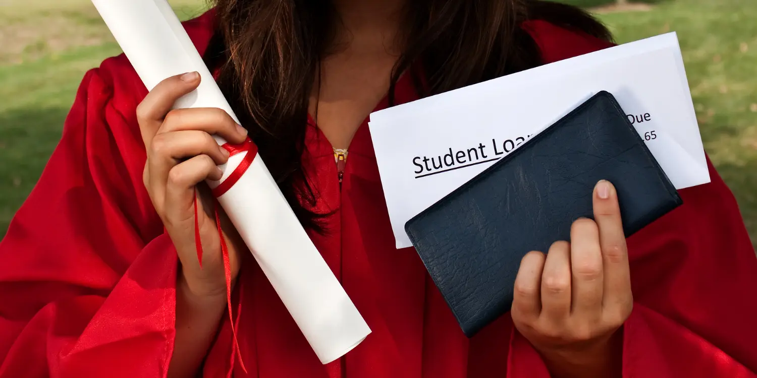 A student in a graduation gown holding a diploma and an evelope for student loan payment collections.