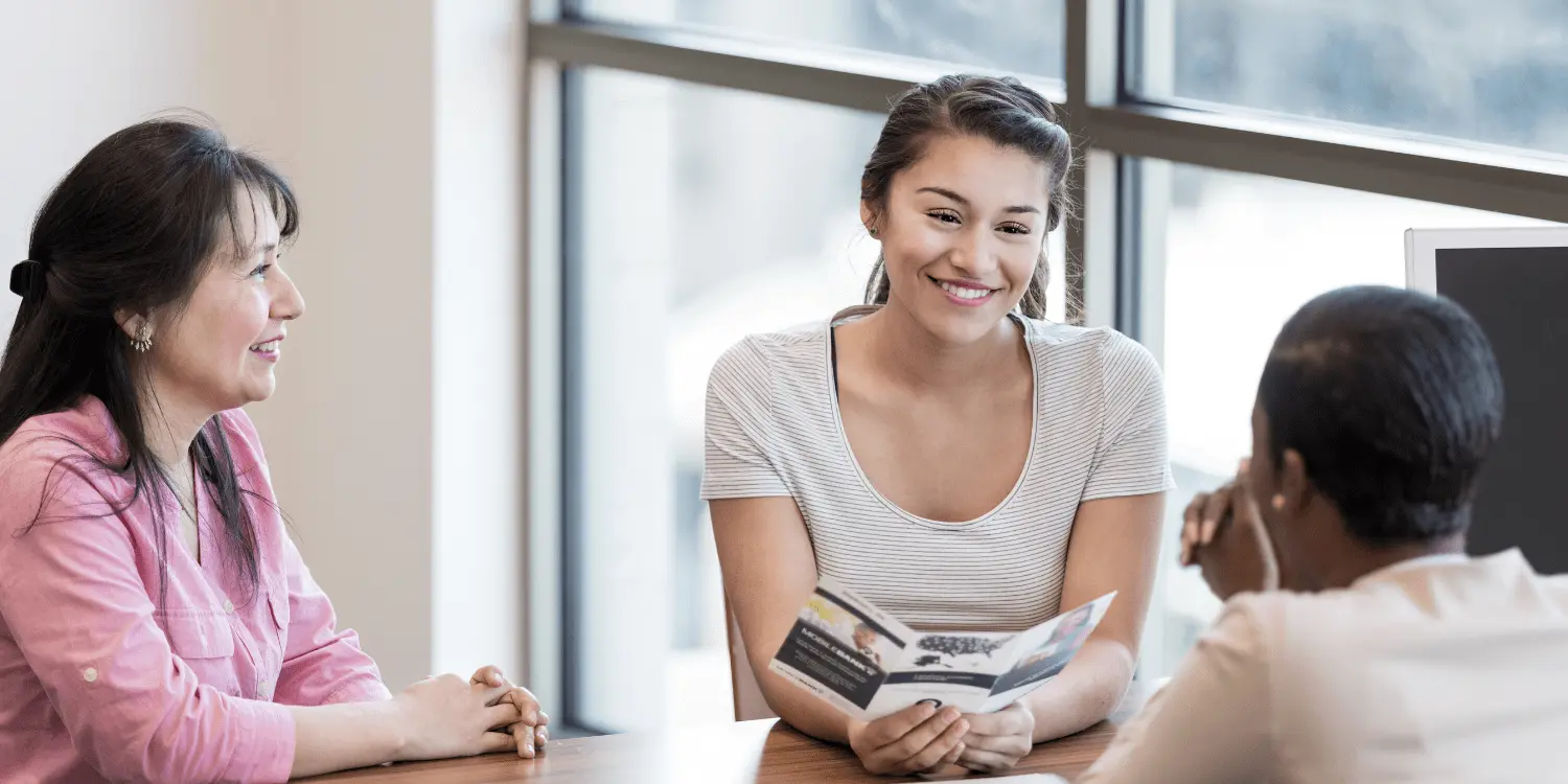 Student talking to student loan officers in a common room.