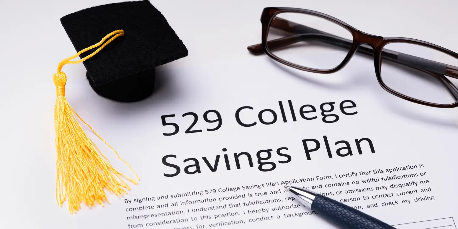 A 529 college savings plan form that has a graduation hat, a pen, and glasses on top of it.
