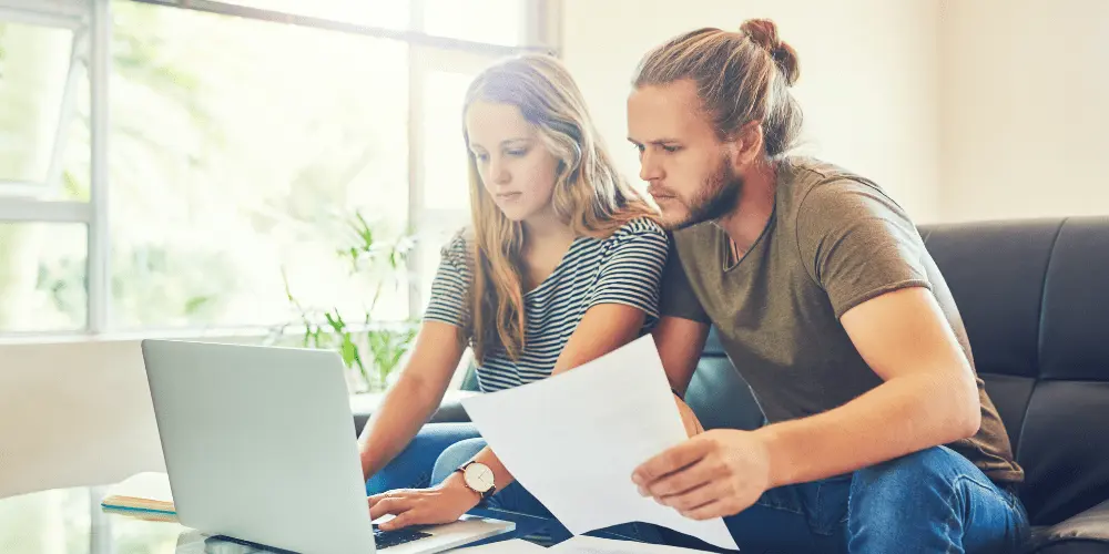 Young renters reviewing documents and using a rent calculator online before leasing an apartment.