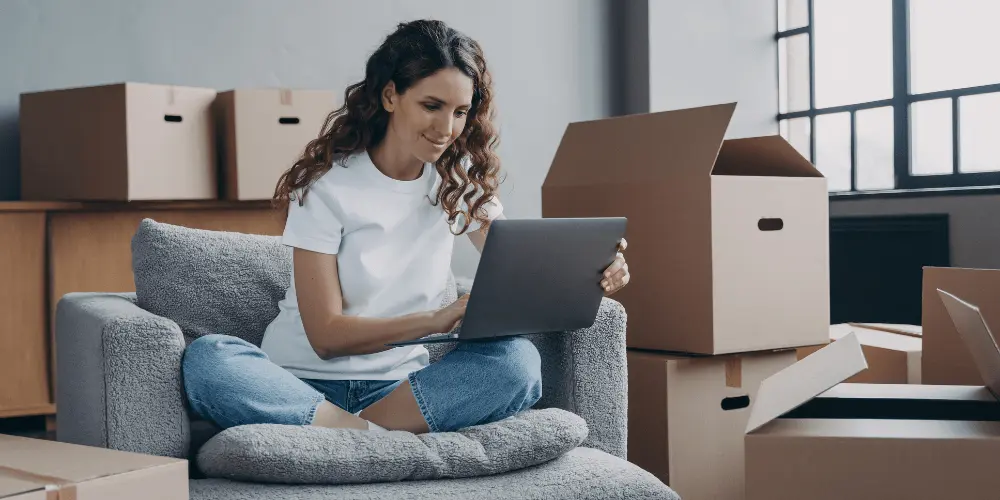 Renter surrounded by boxes on laptop, exploring ways to build credit history without a credit card.