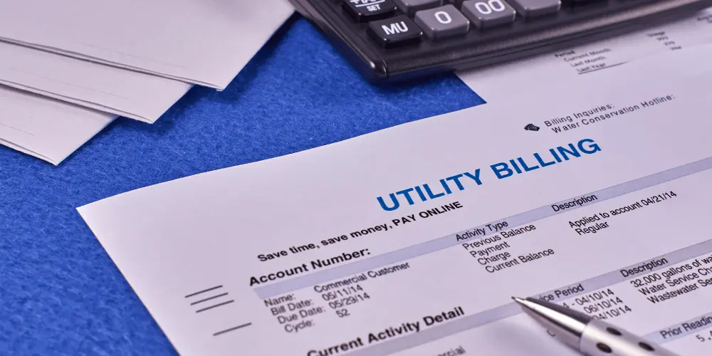 Utility bill on a desk with paperwork and calculator, showing the risk of eviction for unpaid utility bills.