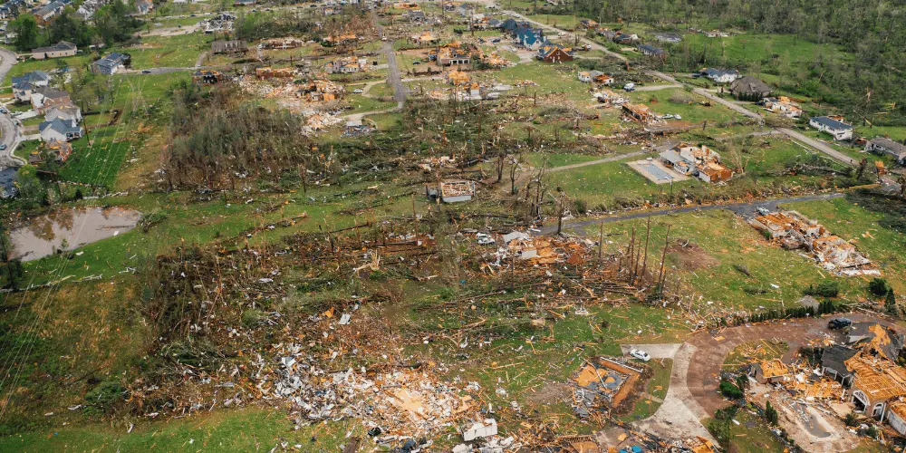 Neighborhood devastated by a tornado with debris scattered highlighting the need for a family disaster recovery plan.