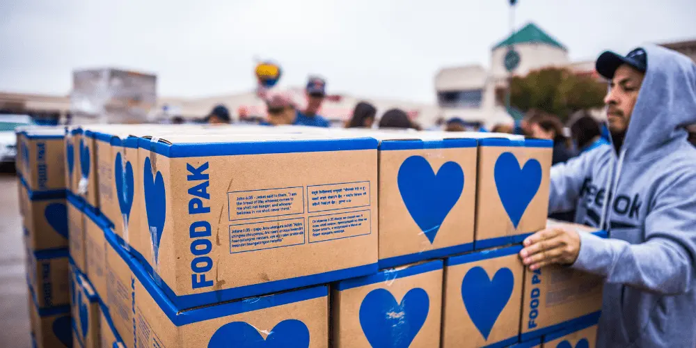 Los voluntarios reparten cajas de alimentos para ayudar en casos de desastre a familias necesitadas en un centro de distribución comunitario local.
