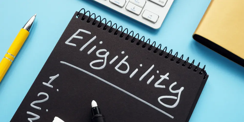 Notebook labeled “Eligibility” beside a pen and keyboard representing FEMA relief qualification requirements.