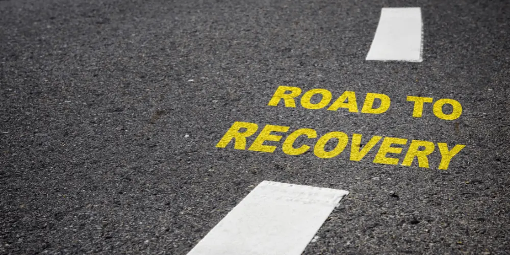 Yellow words “Road to Recovery” on pavement symbolizing FEMA’s support for communities rebuilding after disasters.