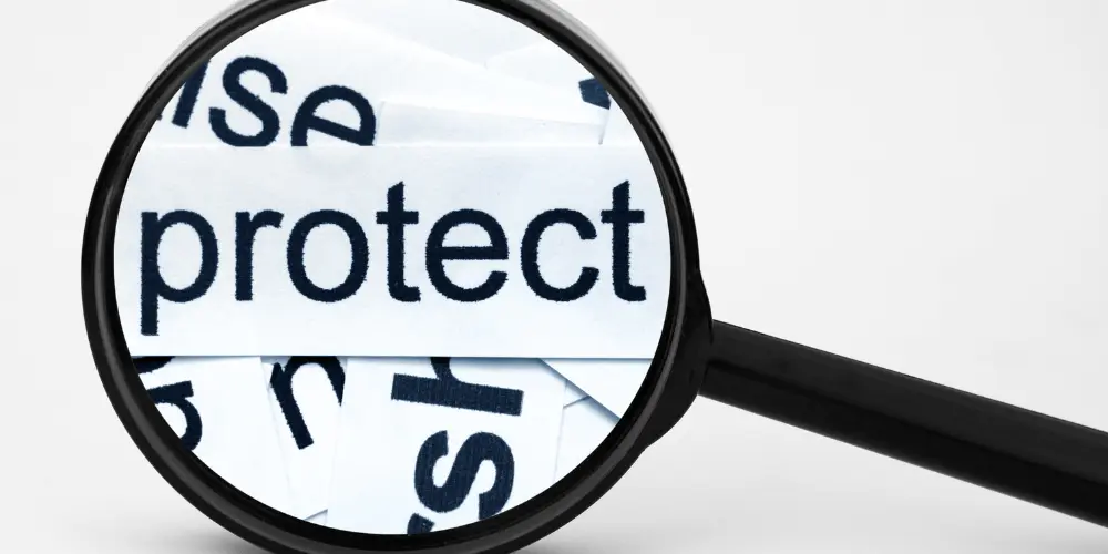 Close-up of the word “protect” under a magnifying glass symbolizing credit protection and financial awareness.