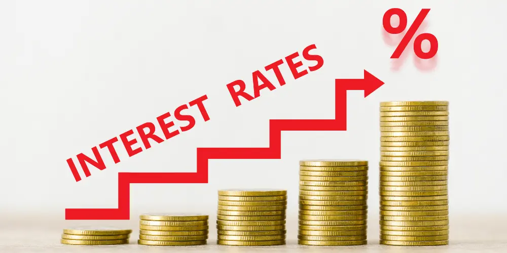 Stacked coins and upward arrow labeled interest rates symbolizing rising mortgage rates for homebuyers.
