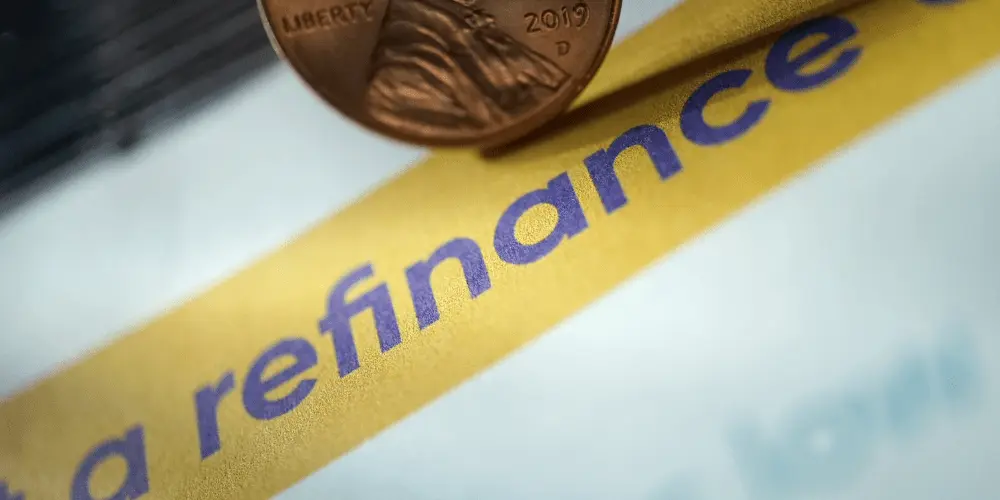 Close-up of paperwork labeled ‘refinance’ with a penny on top, representing the costs and decisions involved in refinancing student loans.