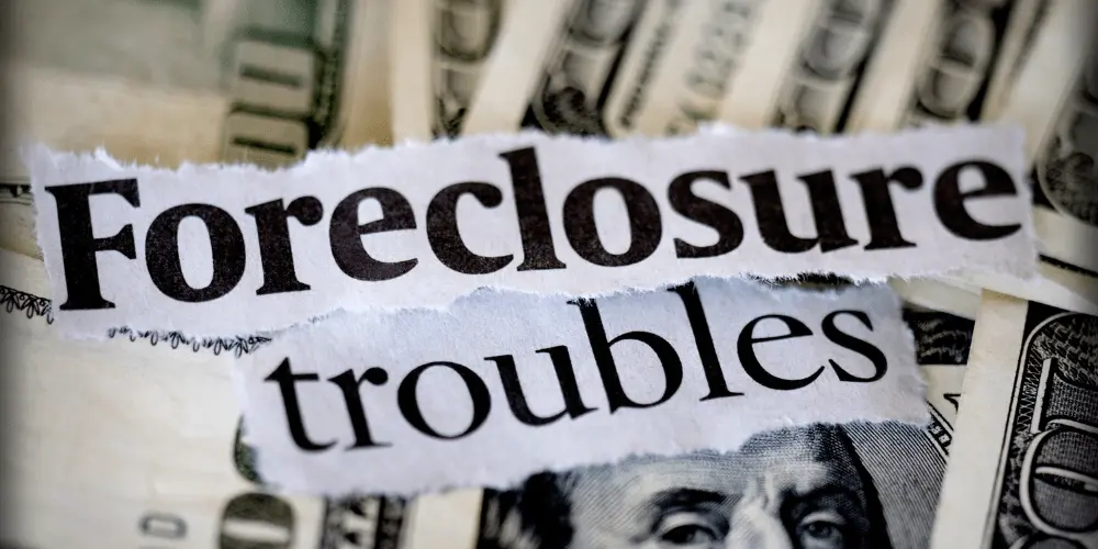 Close-up of the words “Foreclosure troubles” over dollar bills, illustrating financial stress and available government relief options.