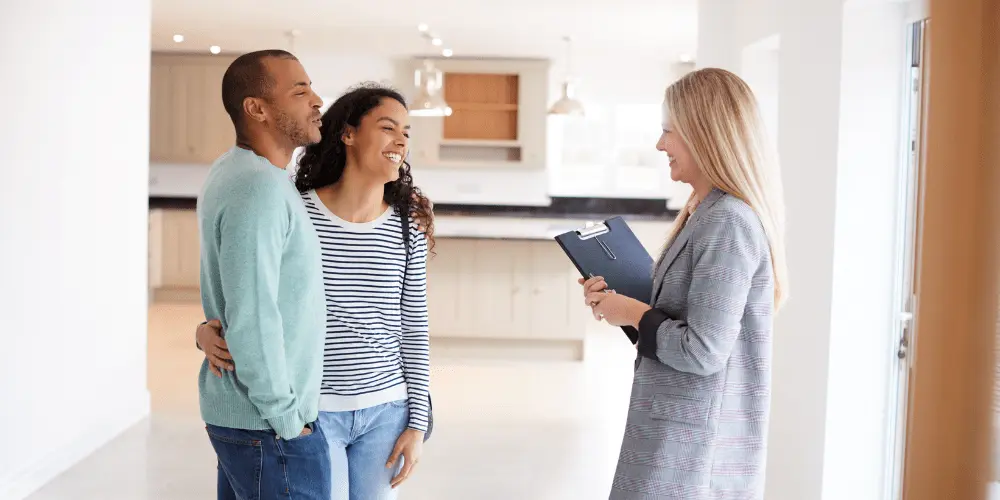 A young couple touring a home with a real estate agent, exploring house hacking options to help lower their monthly mortgage costs.