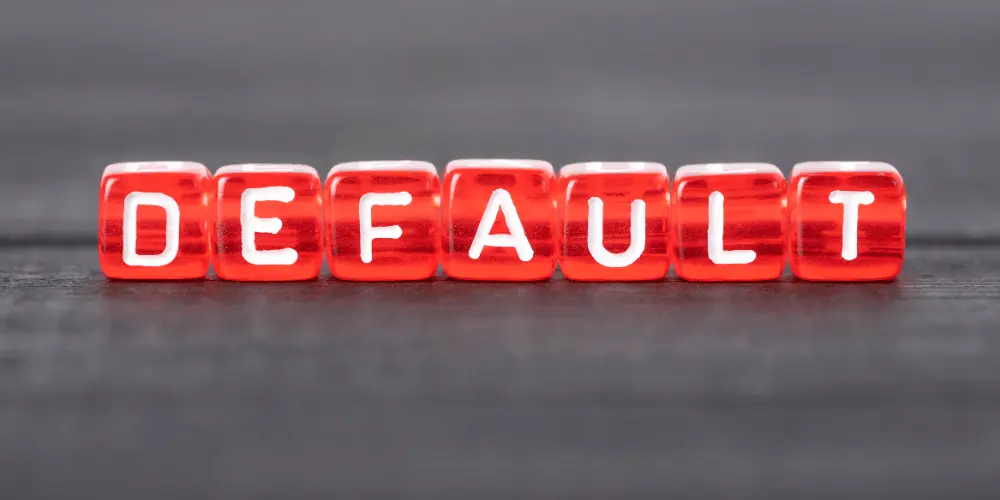 La palabra «incumplimiento» en bloques rojos simboliza el riesgo y la urgencia a los que pueden enfrentarse los herederos cuando vence un préstamo hipotecario inverso.