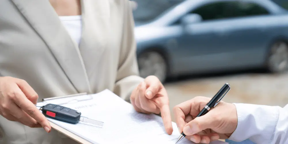 Reviewing paperwork at a dealership highlights the process of trading in a car when it still has value.