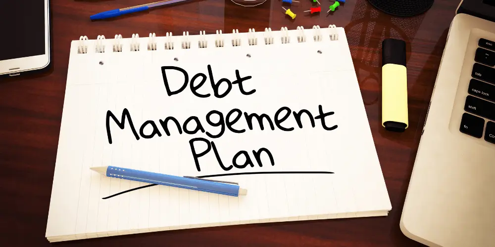 Debt management plan written on a notebook represents organized repayment and how a DMP can support long-term credit health.