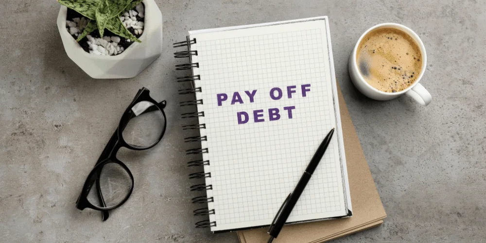 Pay off debt note on desk, showing a written debt payoff plan that can free up money for savings