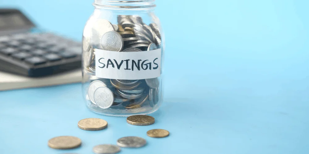 Jar labeled savings filled with coins, showing simple ways to start saving money and build a financial safety net