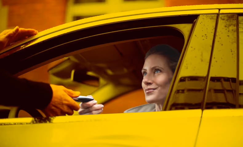 Eine Frau sitzt in einem Auto und bekommt von einer Hand den Fahrzeugschlüssel für den Ersatzwagen gereicht.