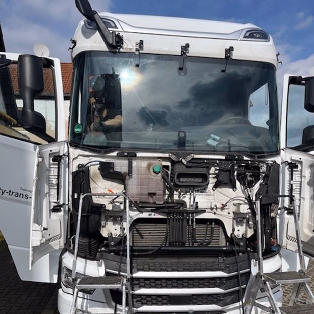 Lkw mit geöffneter Front und ausgebauten Teilen beim Windschutzscheibentausch
